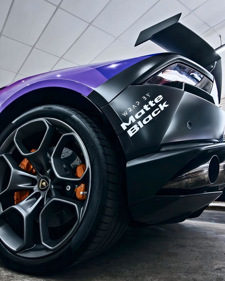 Rear of a purple and matte black Lamborghini Huracan with a WRAP BY Matte Black decal behind the wheel