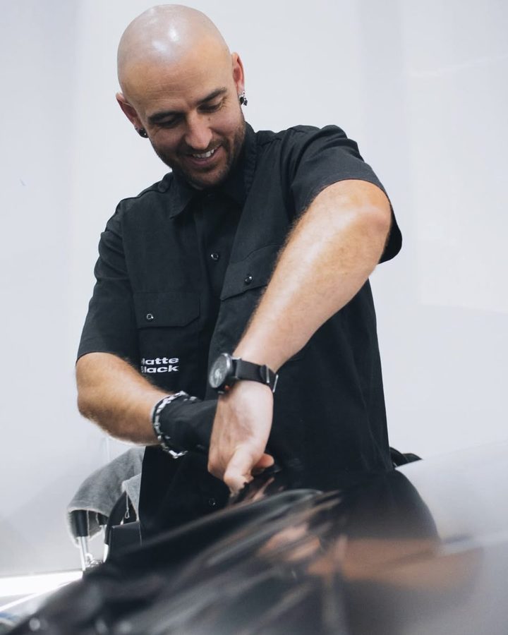 Matt in a Matte Black work shirt fitting film to a black car
