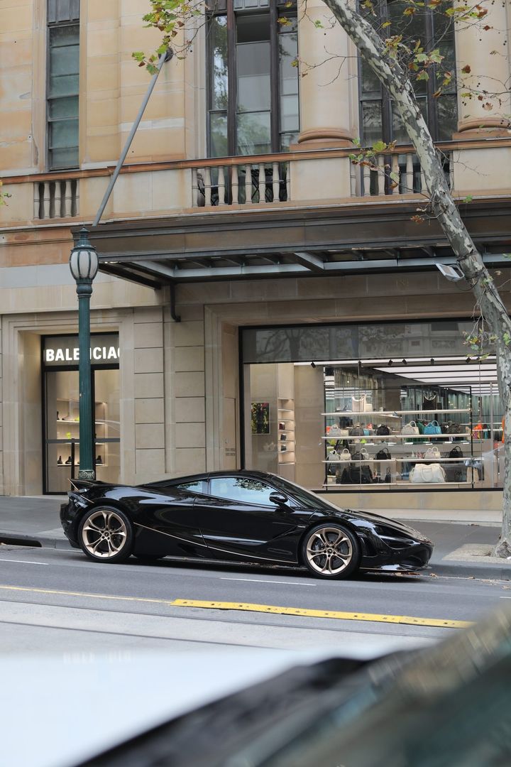 Black McLaren 720S with bronze wheels parked on a city street