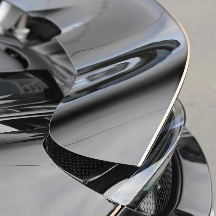 Close-up of a gold pinstripe along the rear wing edge of a black McLaren 720S